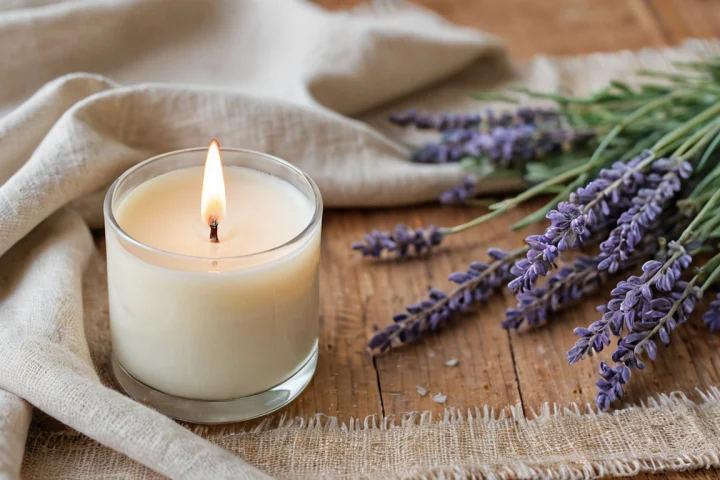 Frische Blüten und eine helle Kerze — Beitragsbild zu „Was bedeutet die Flamme in der Kerzenmagie?“
